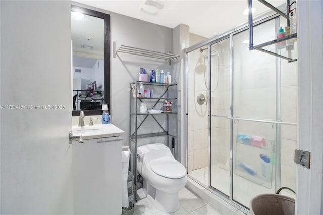 bathroom featuring toilet, vanity, tile patterned floors, and a shower with door