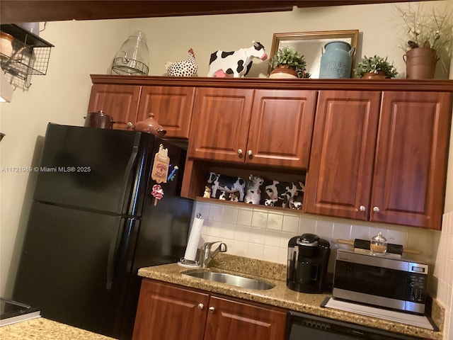 kitchen featuring decorative backsplash, black refrigerator, and sink