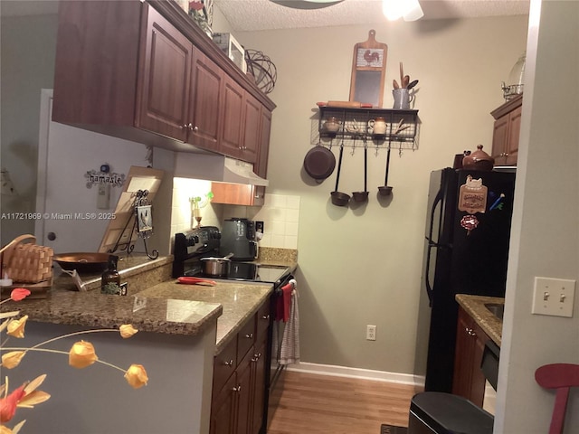 kitchen featuring black appliances, light hardwood / wood-style flooring, a textured ceiling, tasteful backsplash, and stone countertops