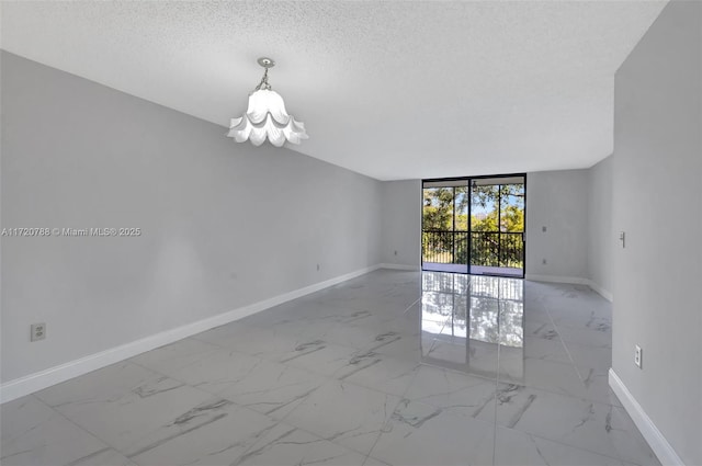 unfurnished room featuring a notable chandelier, expansive windows, and a textured ceiling