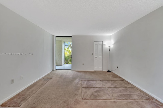 spare room with light carpet, a textured ceiling, and a wall of windows