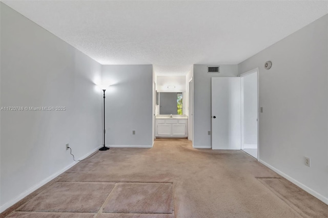 unfurnished room with a textured ceiling and light colored carpet