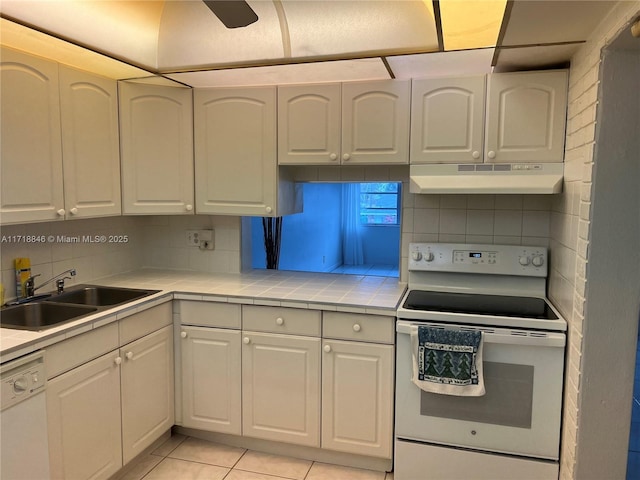 kitchen with decorative backsplash, white appliances, sink, white cabinetry, and light tile patterned flooring