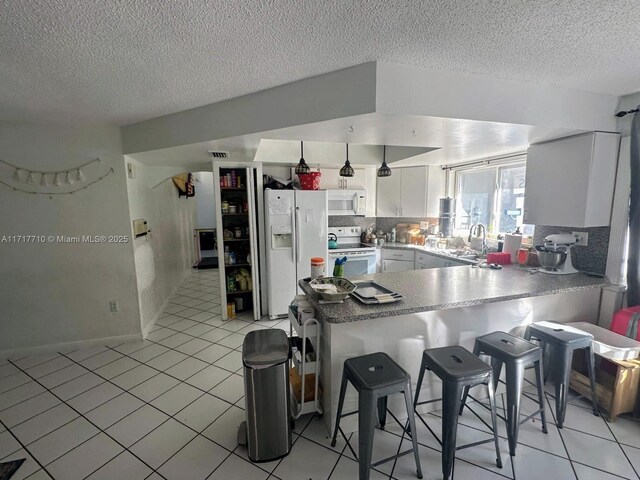 10331 SW 135th Ct, Miami, FL 33186 - kitchen featuring backsplash, white cabinetry, white appliances, and kitchen peninsula