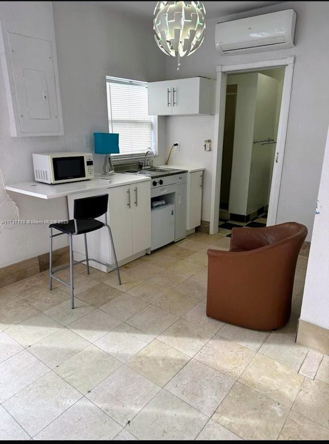 10331 SW 135th Ct, Miami, FL 33186 - kitchen featuring a notable chandelier, white cabinetry, an AC wall unit, pendant lighting, and electric panel