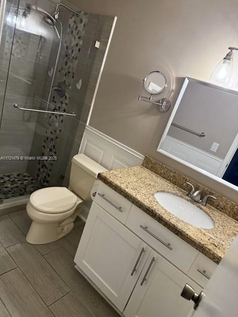 3426 Theo Way Unit 3426, West Palm Beach, FL 33417 - full bath featuring a stall shower, toilet, vanity, wainscoting, and wood finished floors