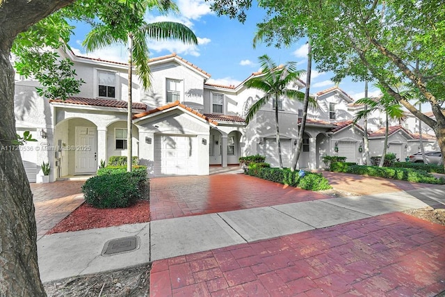 mediterranean / spanish house featuring decorative driveway, stucco siding, a tiled roof, and a residential view