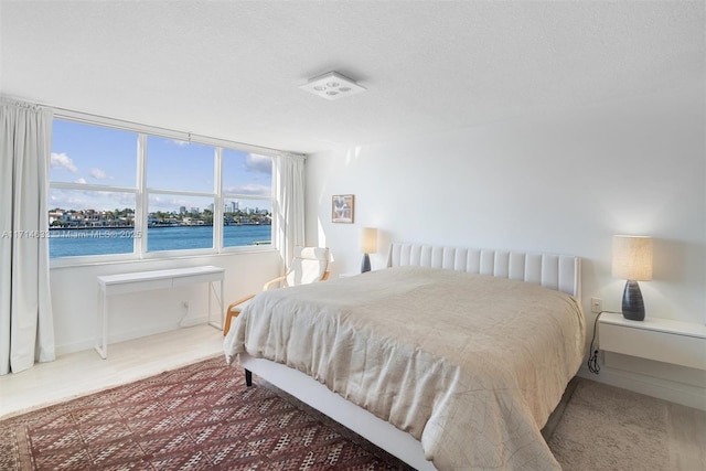 bedroom featuring a water view and a textured ceiling