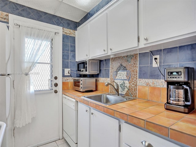 kitchen featuring decorative backsplash, white appliances, sink, tile countertops, and white cabinets