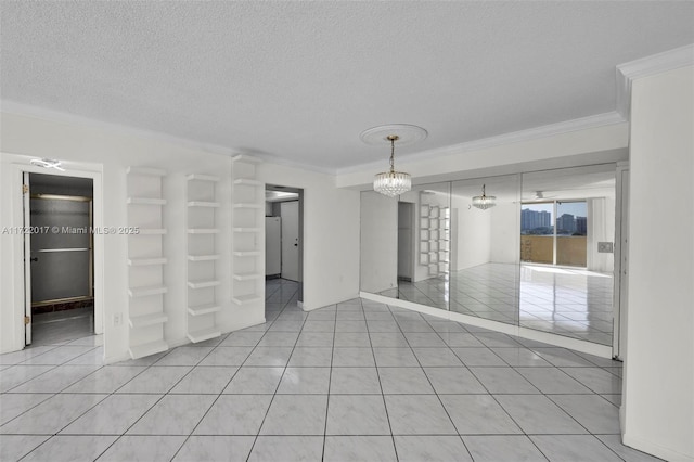 empty room featuring a textured ceiling, an inviting chandelier, crown molding, and light tile patterned flooring