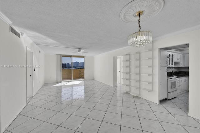 empty room with a textured ceiling, sink, light tile patterned floors, and ceiling fan with notable chandelier