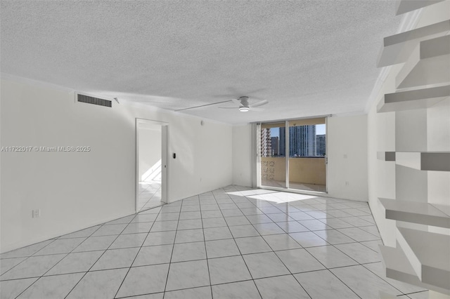 tiled spare room with a textured ceiling and ceiling fan