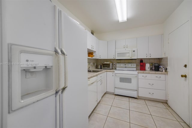 kitchen with white appliances, white cabinets, sink, light tile patterned floors, and tasteful backsplash