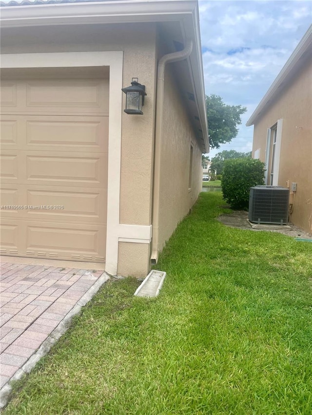 view of property exterior with central AC, a yard, and a garage