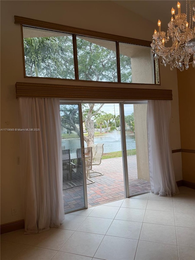 doorway featuring a towering ceiling, light tile patterned floors, a chandelier, and a water view