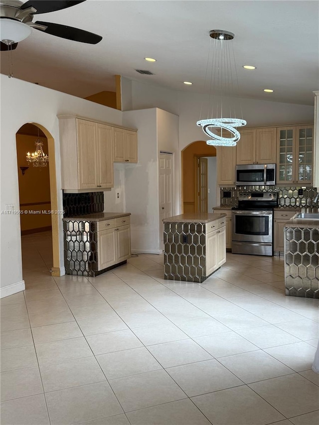 kitchen featuring sink, vaulted ceiling, tasteful backsplash, ceiling fan with notable chandelier, and appliances with stainless steel finishes