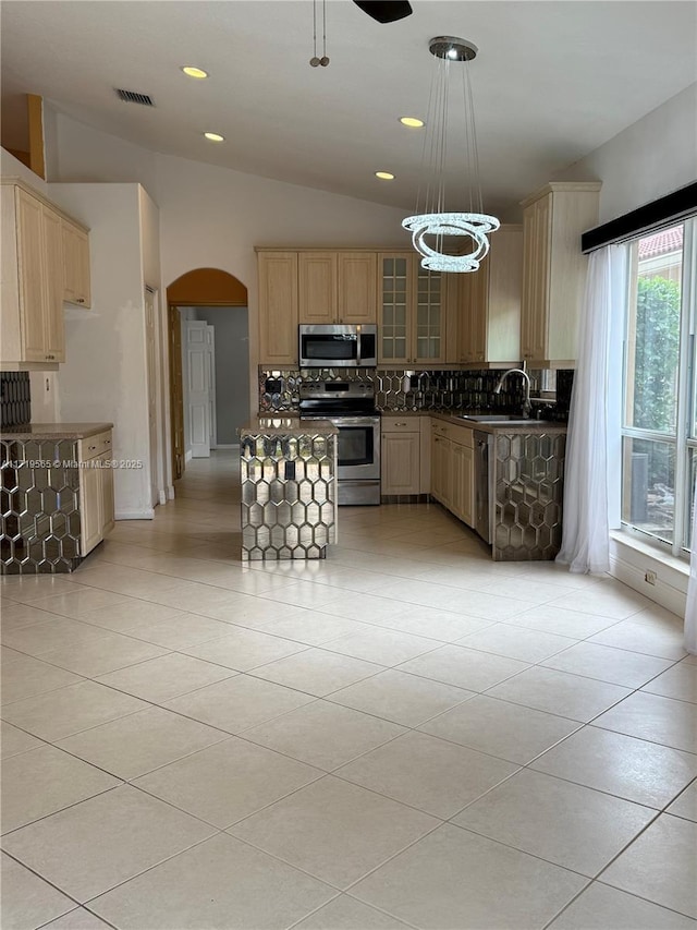 kitchen featuring vaulted ceiling, appliances with stainless steel finishes, light tile patterned floors, pendant lighting, and decorative backsplash