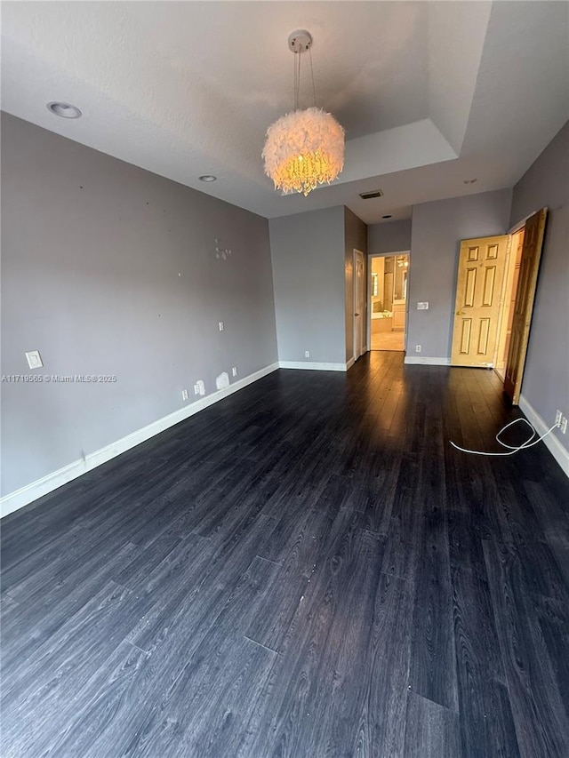 spare room featuring dark hardwood / wood-style flooring and a raised ceiling