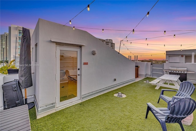 back house at dusk featuring a yard