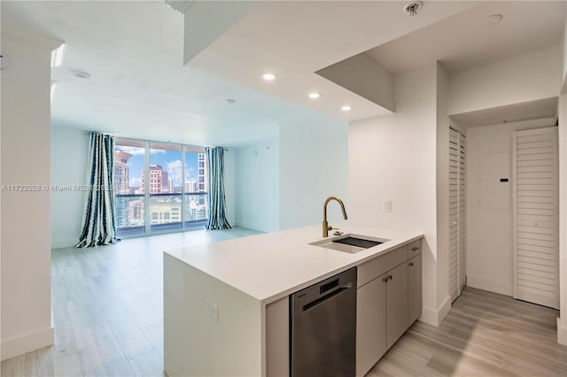 kitchen with kitchen peninsula, light wood-type flooring, floor to ceiling windows, sink, and dishwasher