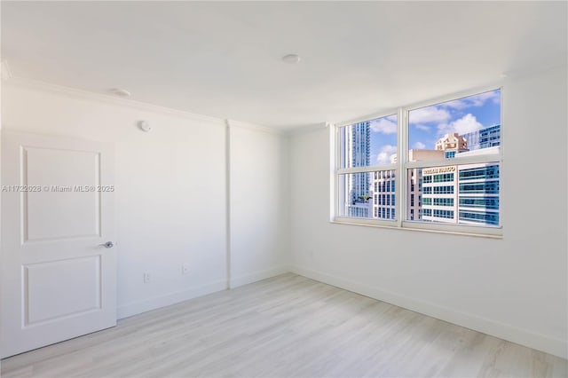 spare room featuring light hardwood / wood-style floors and ornamental molding