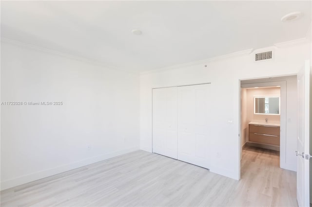 unfurnished bedroom featuring light wood-type flooring, a closet, ornamental molding, and sink