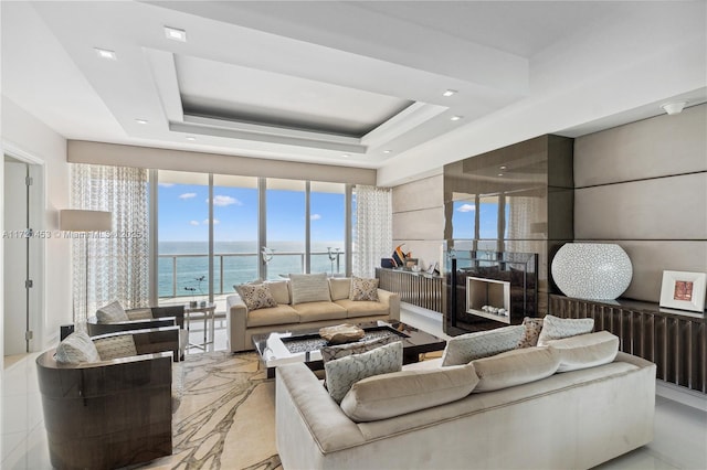 living room with a water view and a raised ceiling