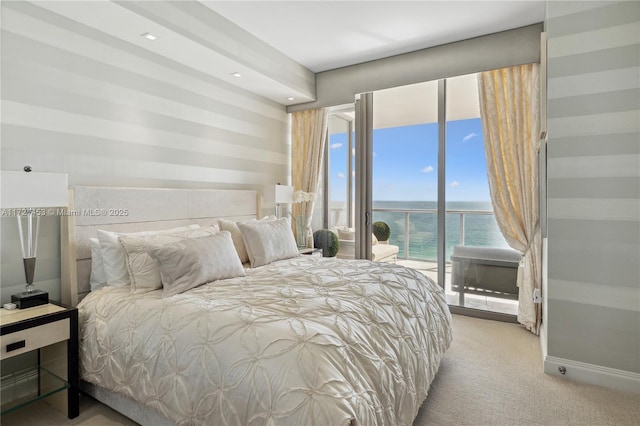 bedroom with light carpet, a water view, and access to outside