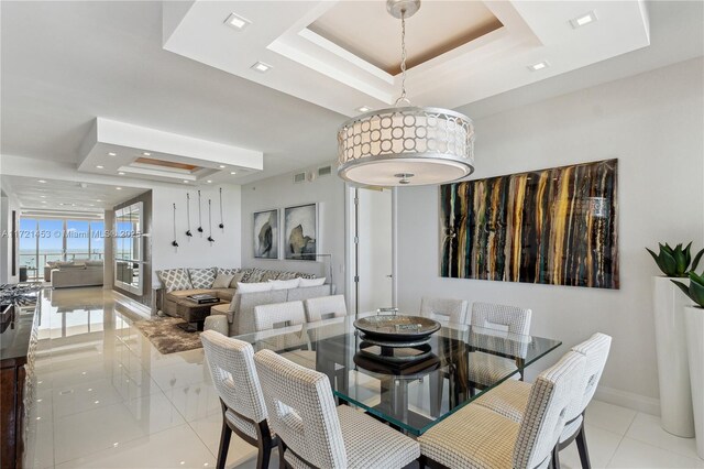 dining area featuring a raised ceiling and light tile patterned flooring