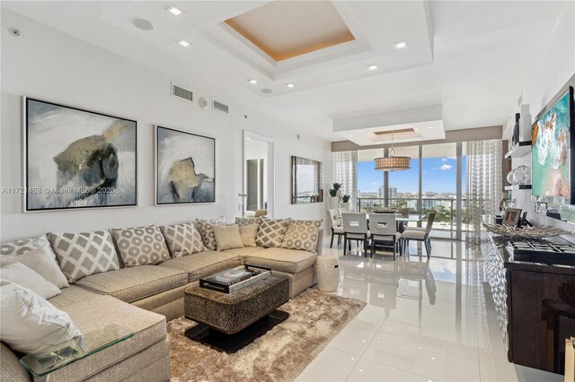 tiled living room featuring a wall of windows and a raised ceiling