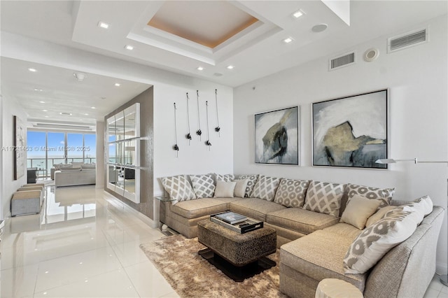 living room with a raised ceiling and light tile patterned floors