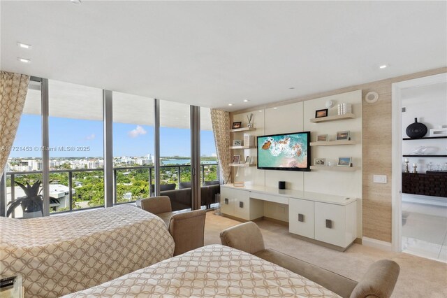 bedroom featuring a wall of windows and light colored carpet