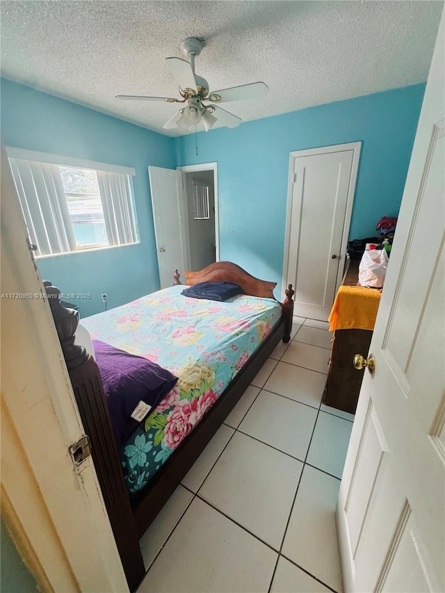 tiled bedroom with ceiling fan and a textured ceiling