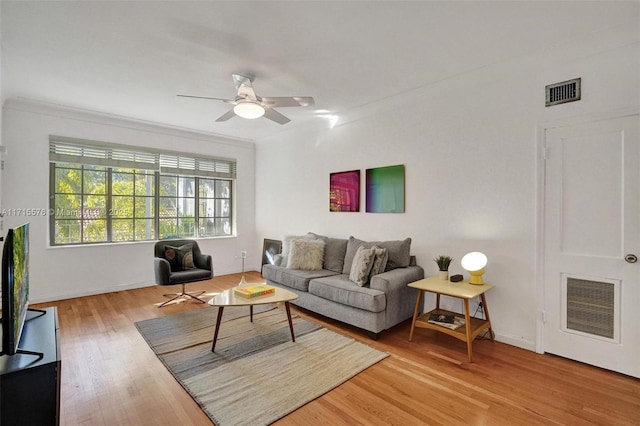 living room with ceiling fan, ornamental molding, and light wood-type flooring