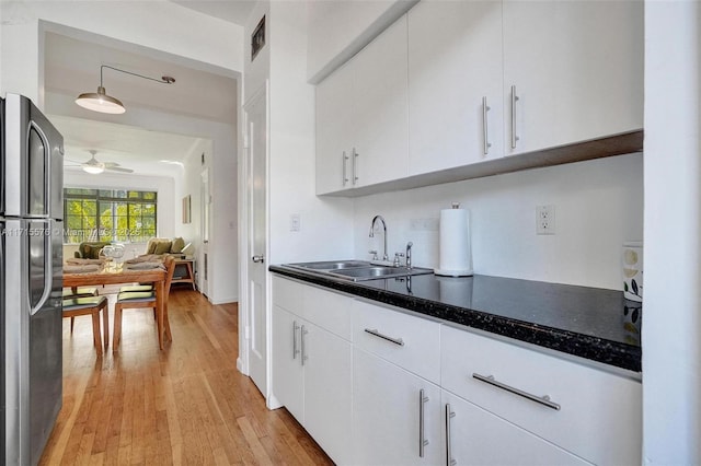 kitchen featuring stainless steel fridge, sink, and white cabinets