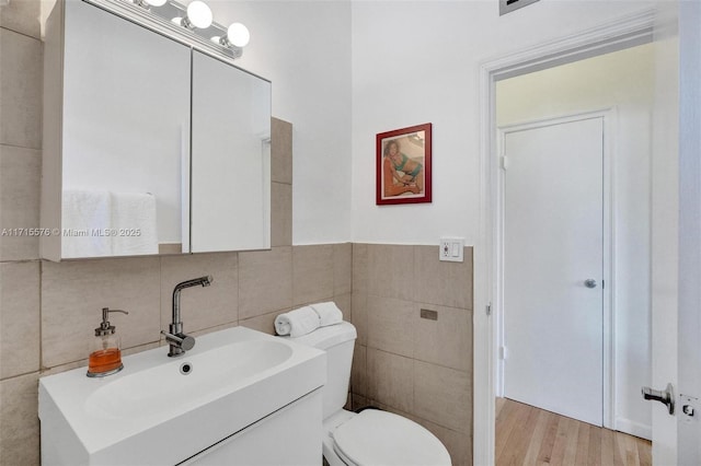 bathroom featuring vanity, wood-type flooring, tile walls, and toilet