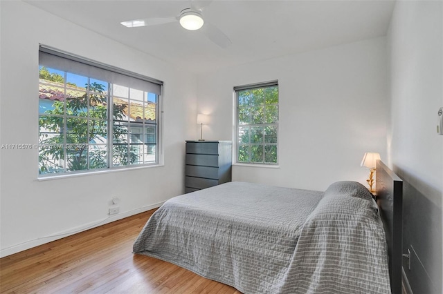 bedroom featuring multiple windows, ceiling fan, and hardwood / wood-style flooring