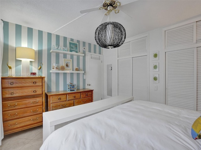 bedroom with ceiling fan, light tile patterned floors, and a textured ceiling