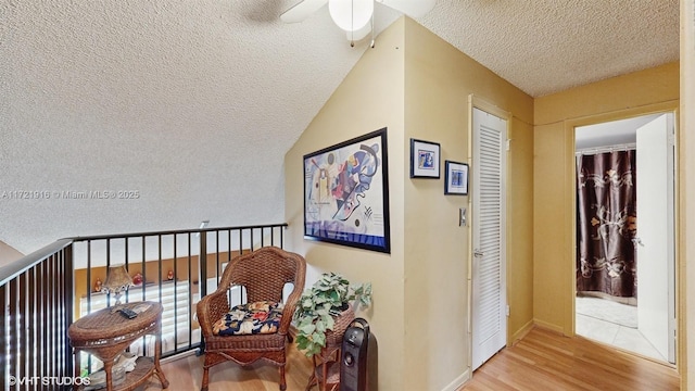 hallway with hardwood / wood-style floors, a textured ceiling, and lofted ceiling