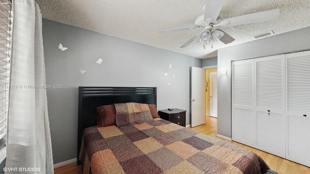 bedroom featuring light wood-type flooring, a textured ceiling, a closet, and ceiling fan