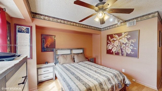 bedroom featuring ceiling fan, light hardwood / wood-style floors, and a textured ceiling