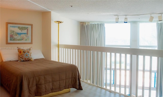 bedroom with multiple windows, rail lighting, and a textured ceiling