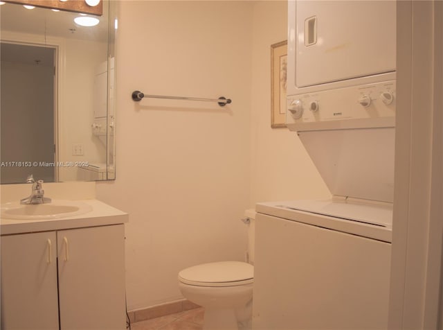 bathroom featuring tile patterned flooring, vanity, toilet, and stacked washer and dryer