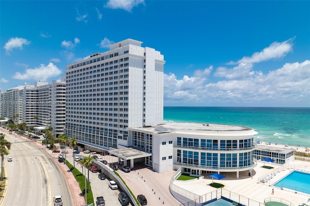 view of building exterior featuring a water view and a beach view