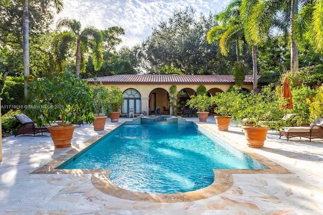 view of swimming pool with an in ground hot tub, a patio, and an outbuilding