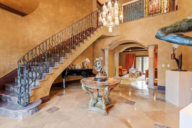 foyer entrance with decorative columns and a towering ceiling