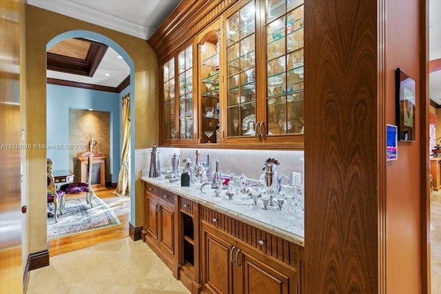 bar featuring light stone counters and crown molding