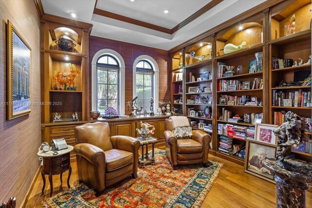 sitting room with light hardwood / wood-style floors, a tray ceiling, and ornamental molding