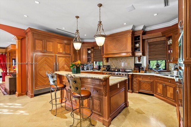 kitchen featuring backsplash, premium range hood, pendant lighting, a kitchen island, and light stone counters