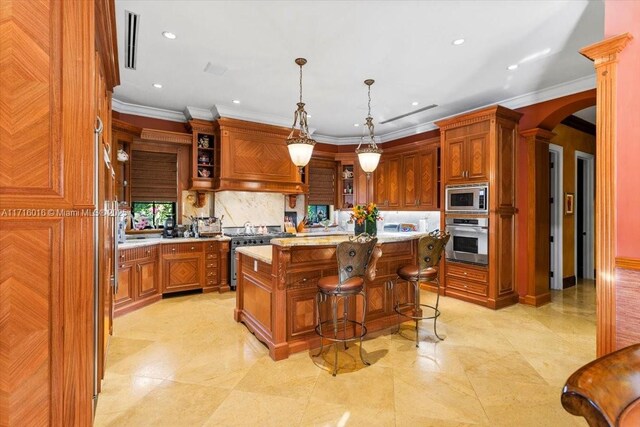 kitchen with a kitchen bar, appliances with stainless steel finishes, a kitchen island, pendant lighting, and decorative backsplash